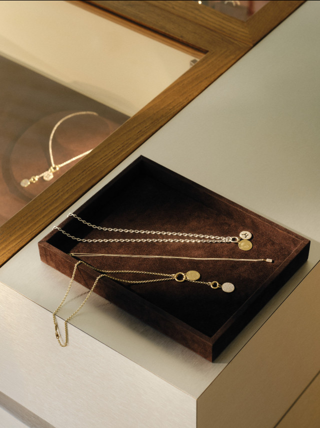 necklaces and bracelets styled on dark brown jewellery display case at otiumberg store