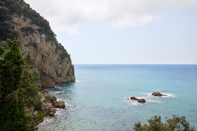 cove area in corfu with rugged hills and trees surrounding it
