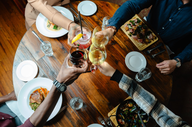 four people clinking wine glasses 