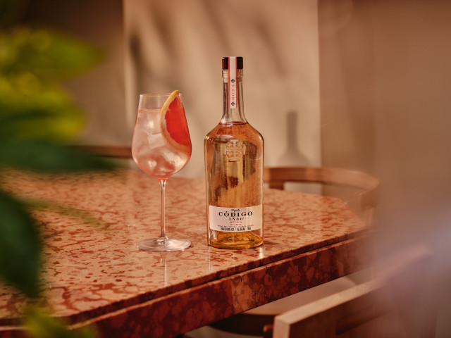 bottle of codigo tequila with cocktail topped with a slice of grapefruit