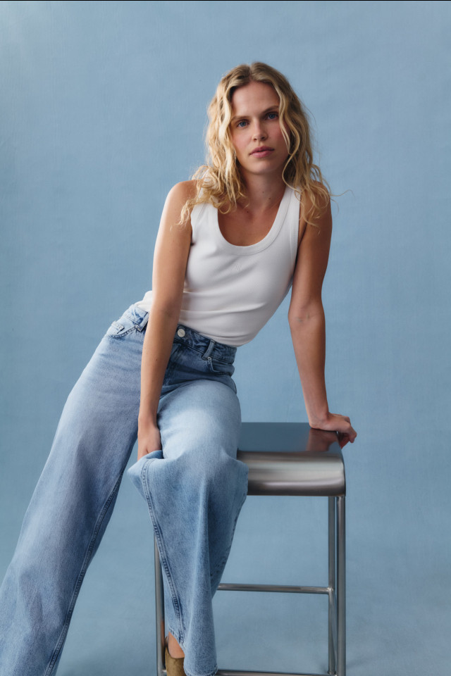 model posing in white tank and blue jeans