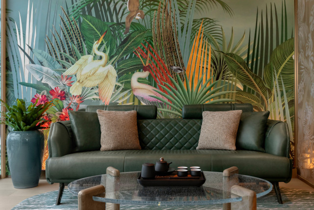 green sofa with jungle wallpaper behind it
