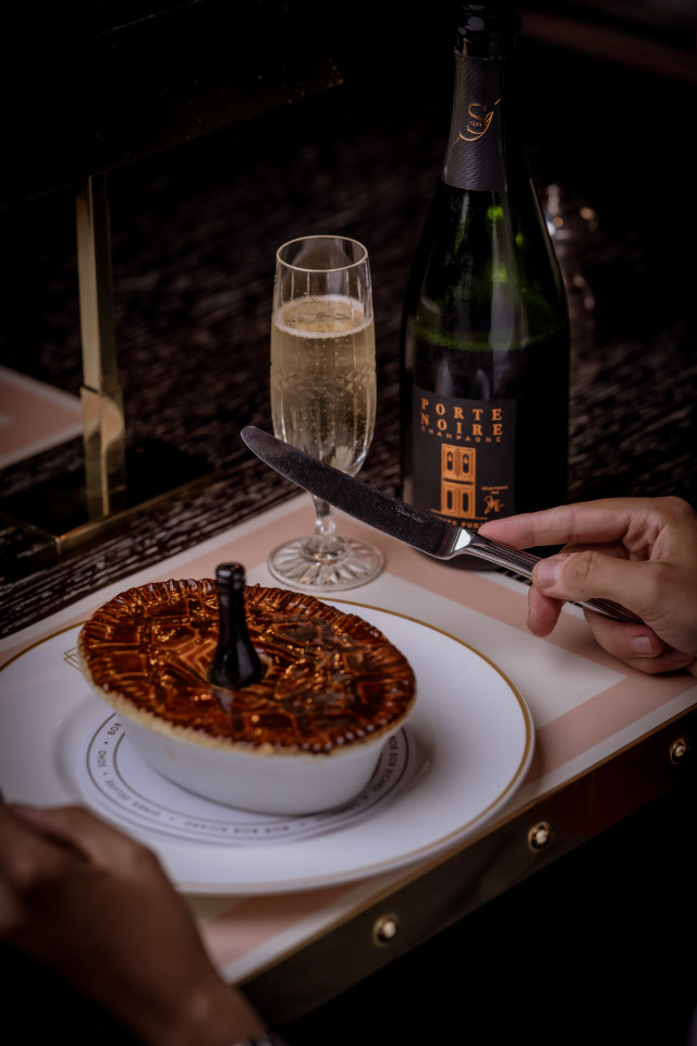 person in restaurant with pie and glass of fizz 