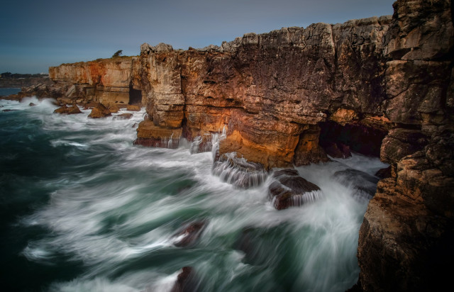 Boco do Inferno, a chasm located in the seaside cliffs of Cascais. The seawater has access to the deep bottom of the chasm and vigorously strikes its rocky walls, making it a popular tourist attraction.