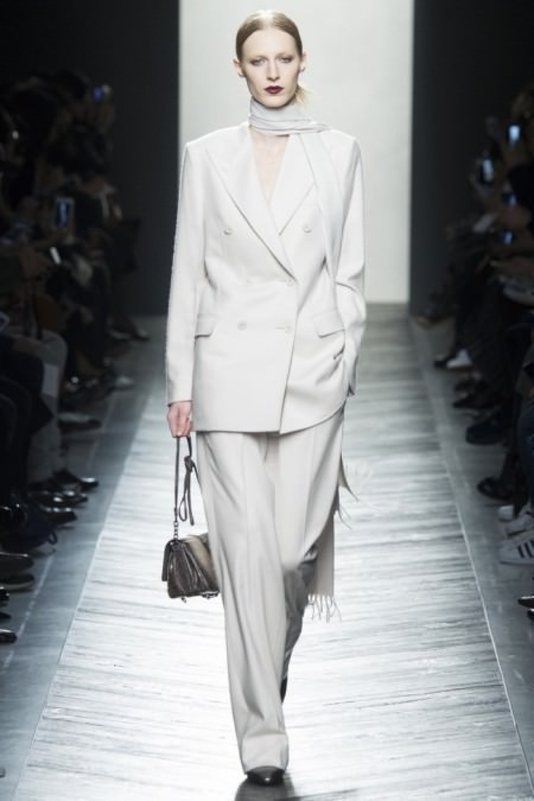 Model in white suit walking down the runway at a fashion show