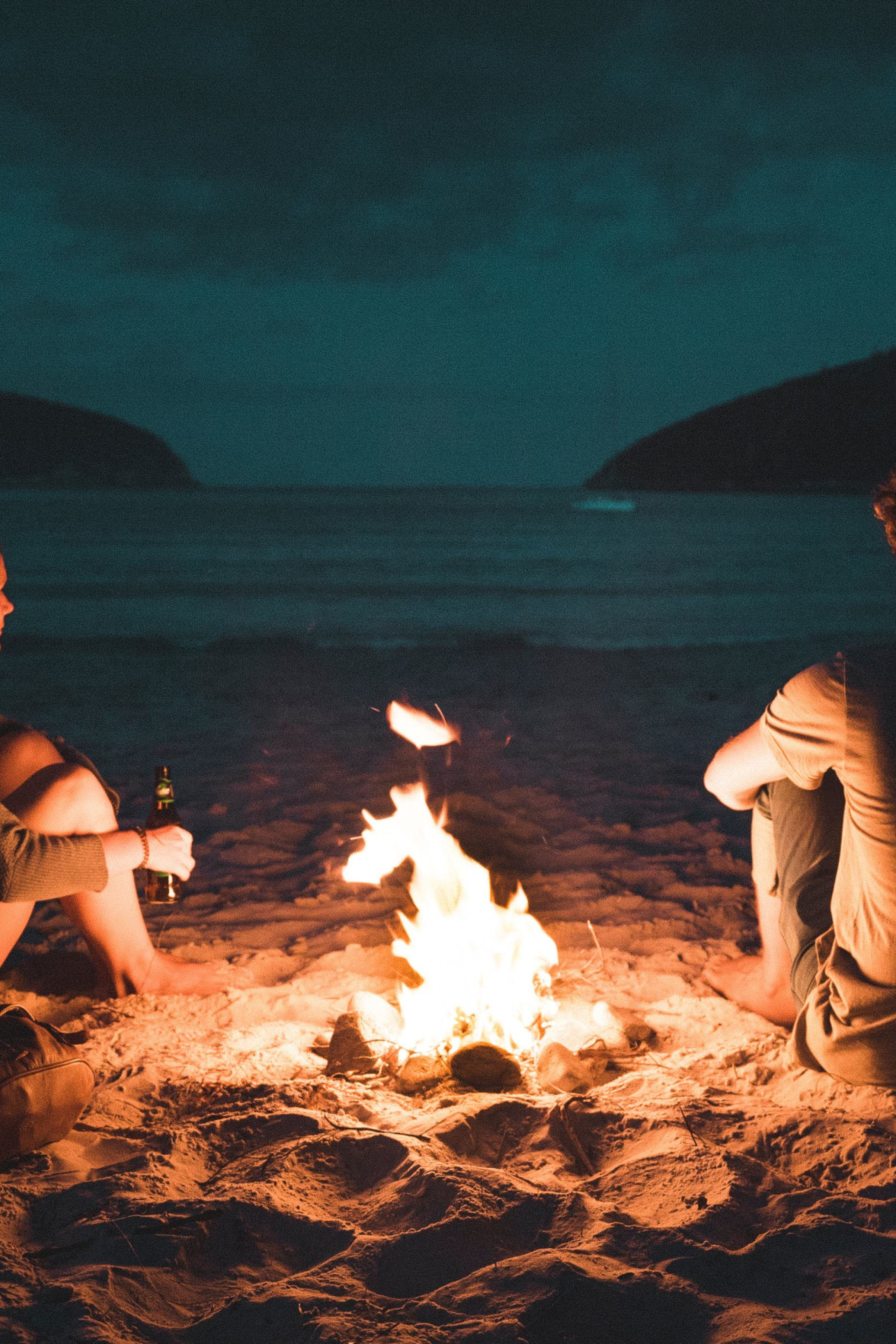 couple-sat-at-a-campfire-by-the-sea.jpg