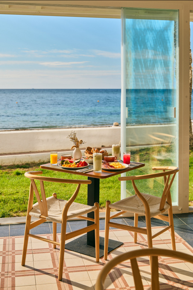 hotel table laid with breakfast and complete with a sea view