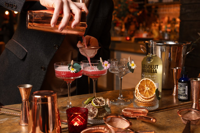 three cocktails surrounded by cocktail making tools and ingredients