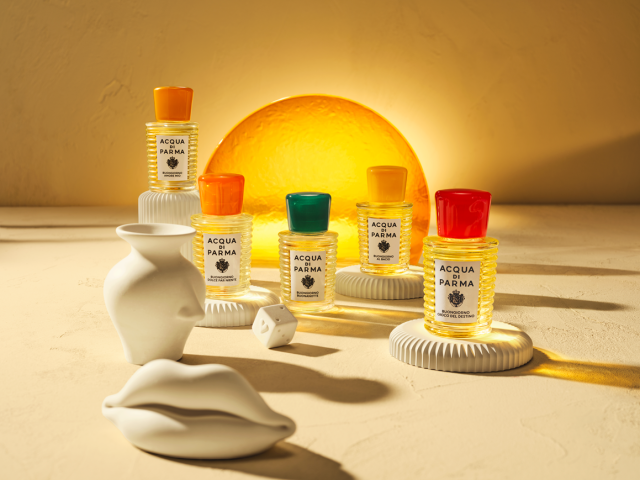 five perfumes in a line with sun motif in the background