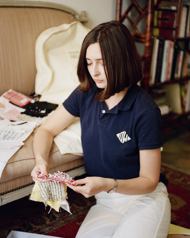 portrait of delia wade sat on apartment floor looking at fabrics