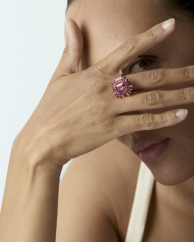 photo of model wearing pink ring and posing with hand over one eye 