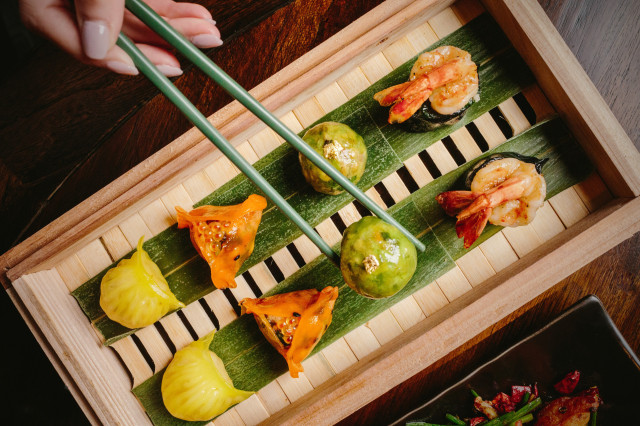 person using chopsticks to eat dim sum platter