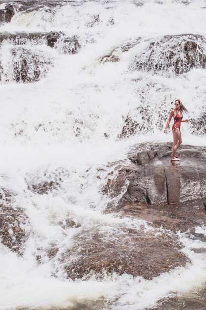 Adventurous woman standing on white water rocks.