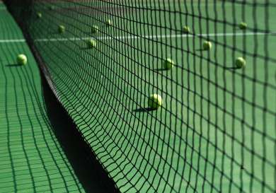 Tennis balls scattered on a court on either side of the net.
