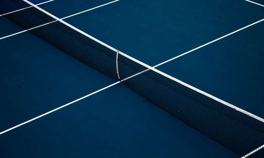 Blue tennis court with net set up.