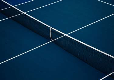Blue tennis court with net set up.