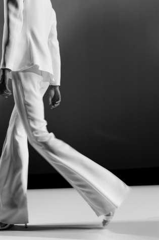 Model walking on catwalk in trouser suit.