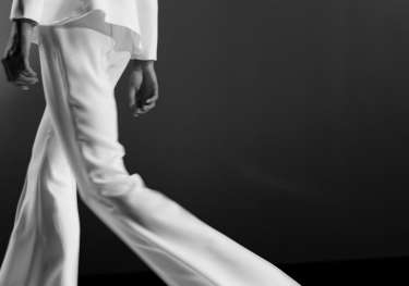 Model walking on catwalk in trouser suit.