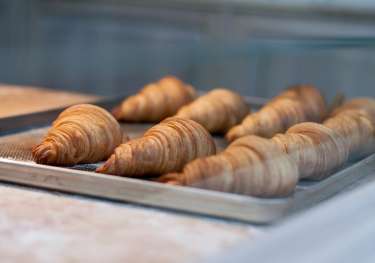 Baked croissants on a metal tray .