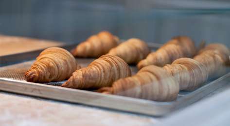 Baked croissants on a metal tray .