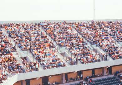 Fans sitting in stands at a tennis match.