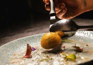 Chef plating up dish in fine dining restaurant .