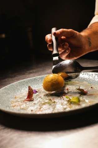 Chef plating up dish in fine dining restaurant .