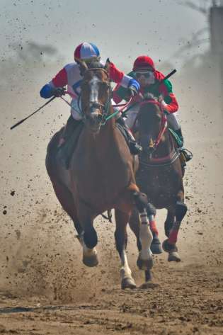 Jockeys racing their horses on a dirt path.