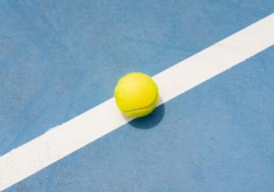 Tennis ball sitting on a blue tennis court.