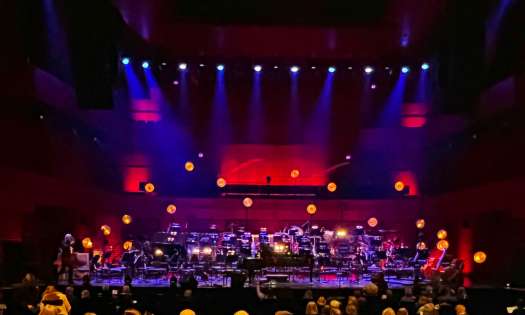 Purple and red lighting on a stage with an orchestra set-up without people.