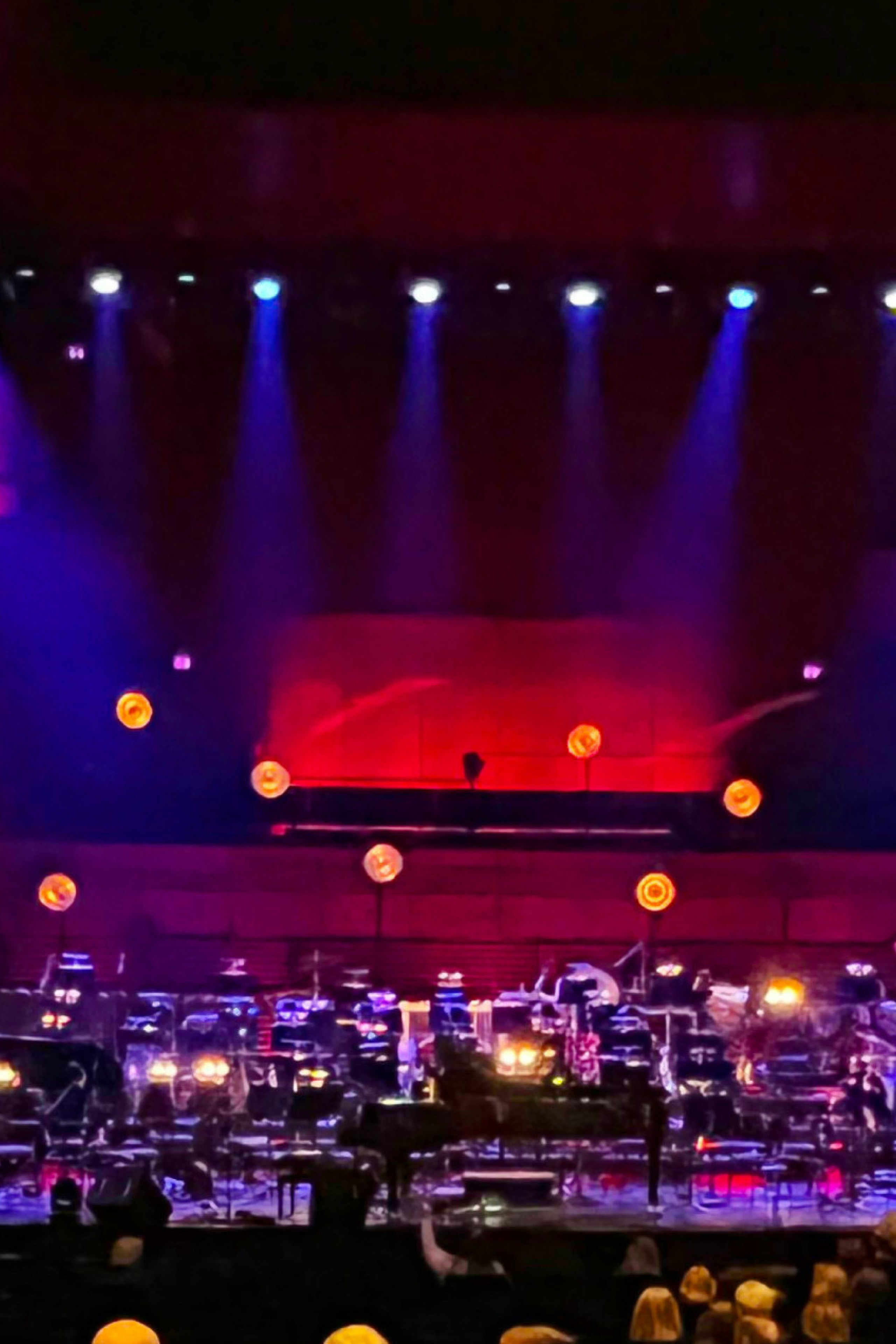 purple and red lighting on a stage with an orchestra set-up without people