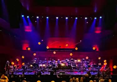 Purple and red lighting on a stage with an orchestra set-up without people.