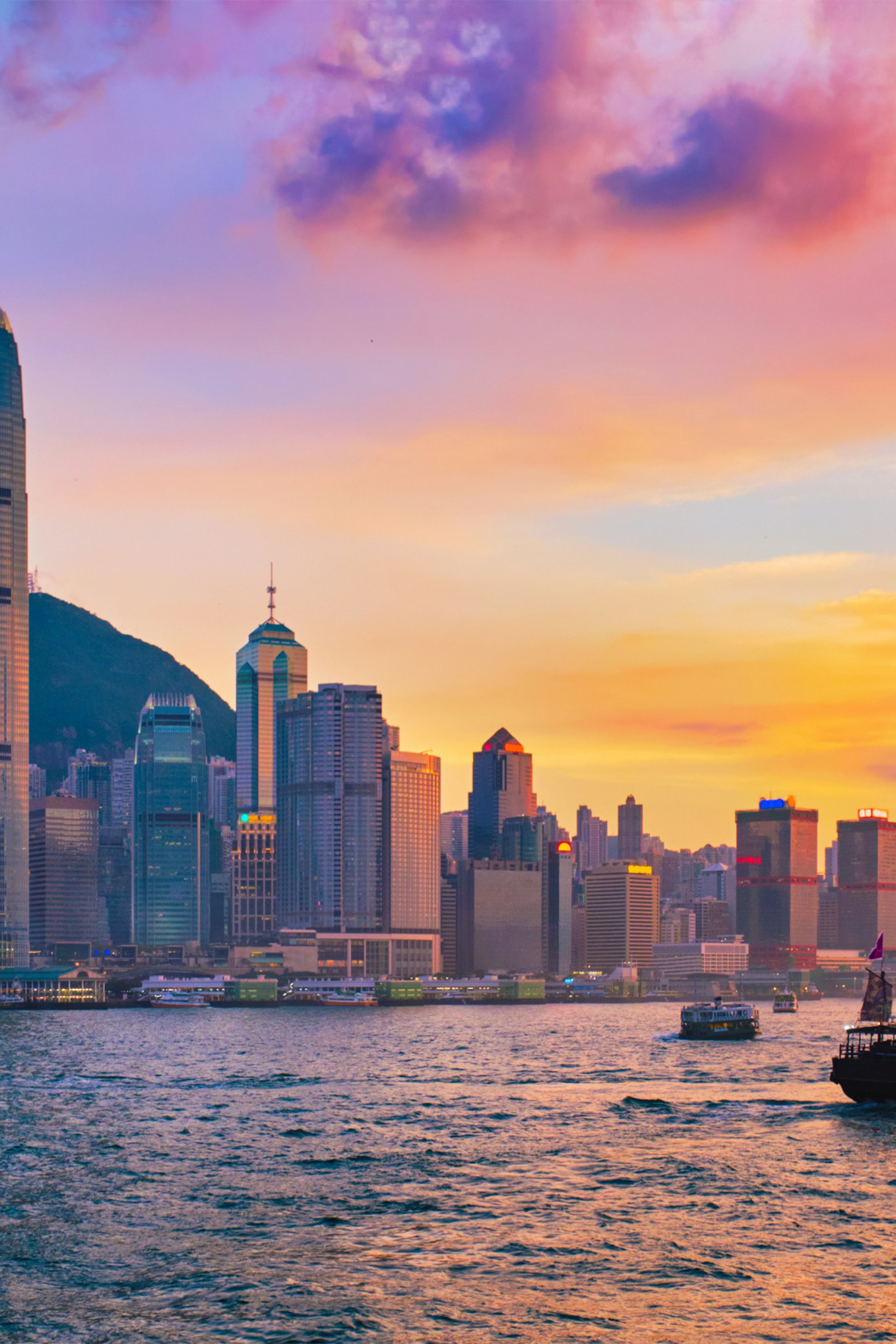 Hong Kong city skyline during sunset with the ocean in front and boats