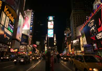 Times square at night, a lot of cars and bright screens.