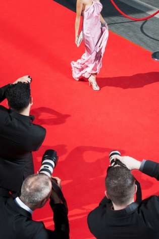 Woman walking down red carpet in pink dress .