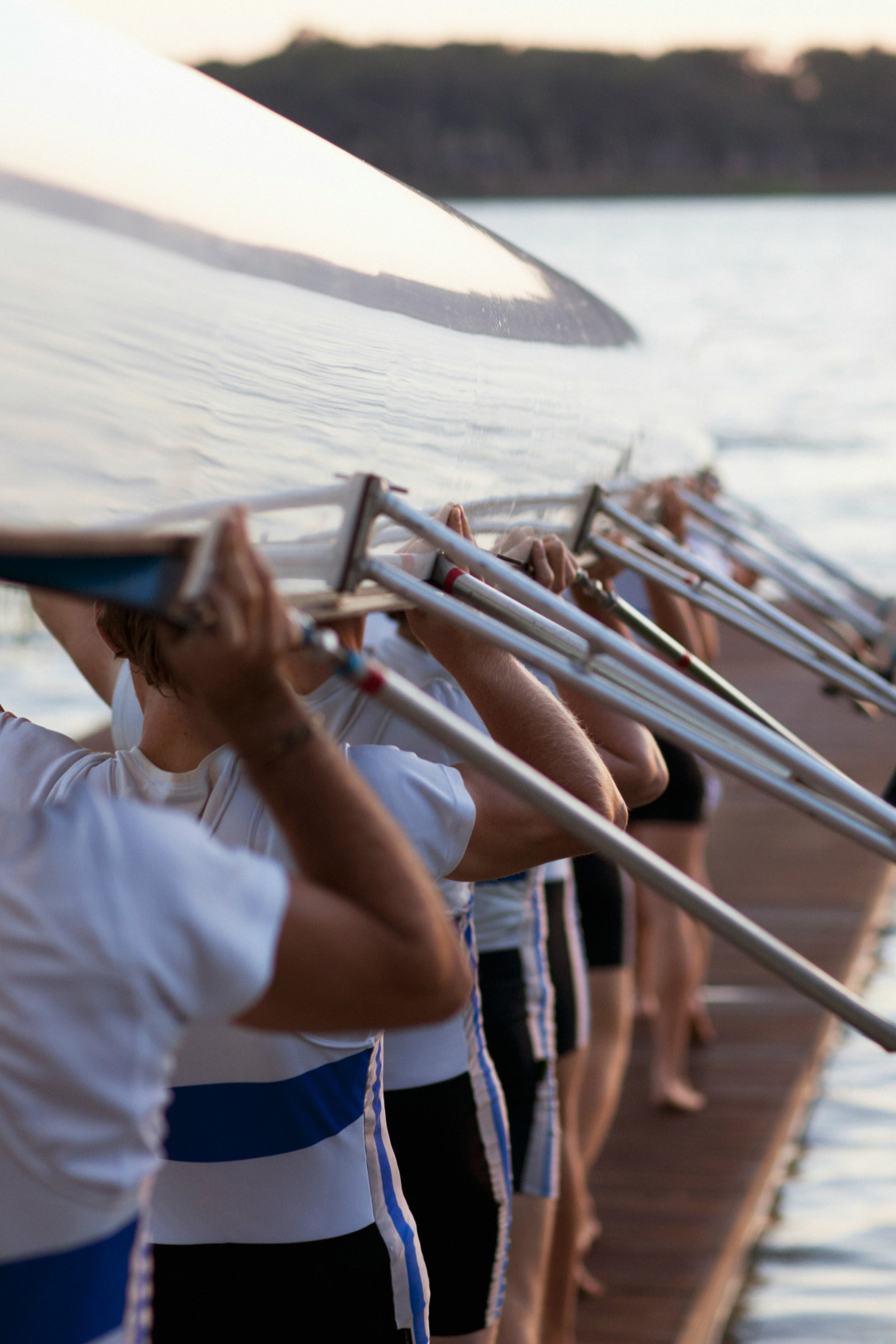 rowers posing with rowing boat above their heads