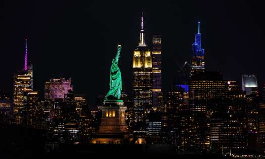 New York City skyline at night with the Statue of Liberty.