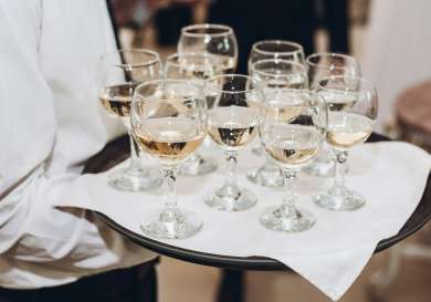 Person holding tray of filled wine glasses.