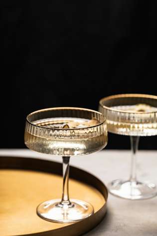 Two glasses of champagne with gold round tray .