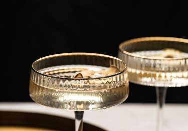 Two glasses of champagne with gold round tray .