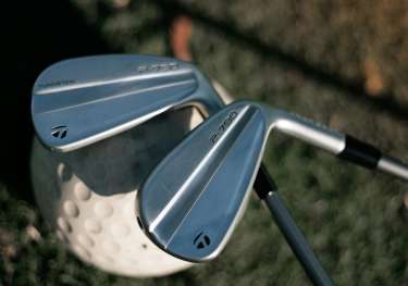 Two golf clubs resting on single golf ball .