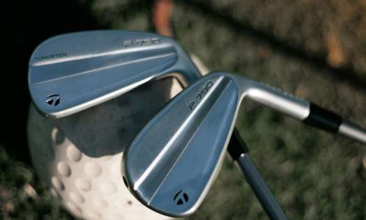 Two golf clubs resting on single golf ball .