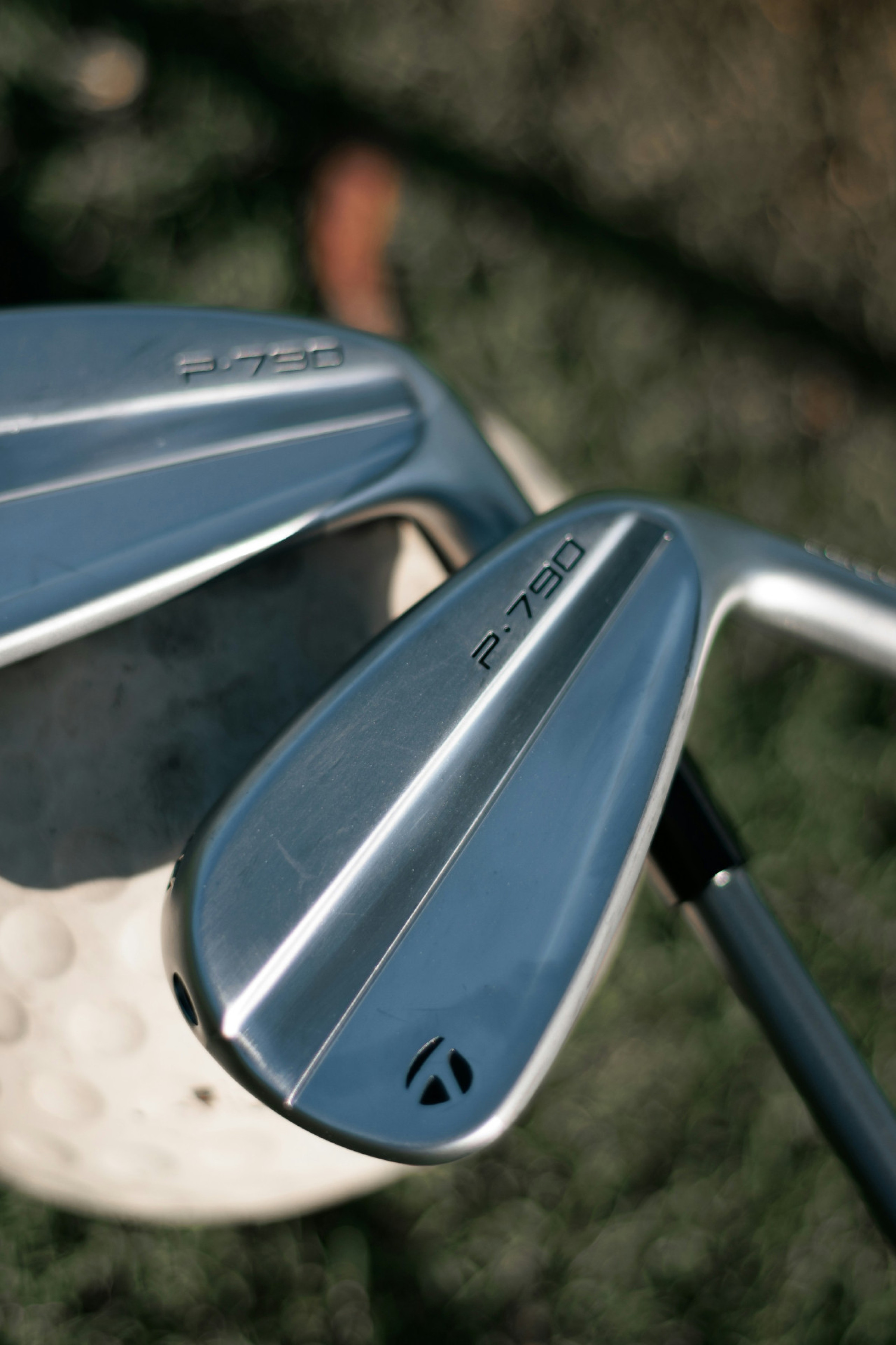 two golf clubs resting on single golf ball 