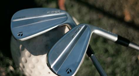 Two golf clubs resting on single golf ball .