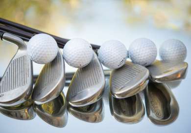 Golf clubs lined up with golf balls .