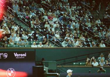 Tennis player on a court with a large audience in the stadium around him.