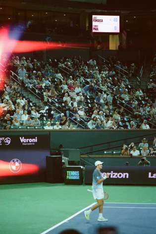 Tennis player on a court with a large audience in the stadium around him.