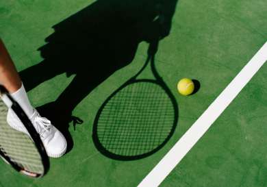 Tennis player with a racket standing over a tennis ball.