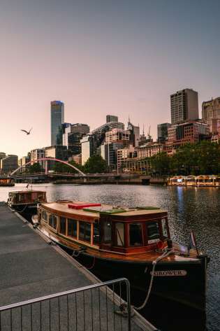 River in Melbourne, Australia with boats in front and buildings in the background.