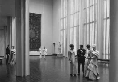 Black and white image of LACMA from the inside with nicely-dressed women and men.